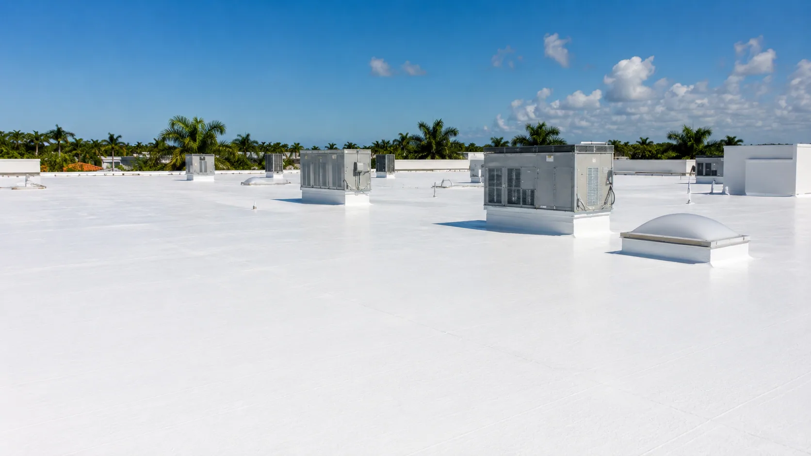 A white-coated commercial roof with rooftop equipment
